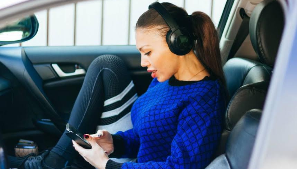 Woman sitting in car on mobile is likely to have faced a location prompt before using the app she's on